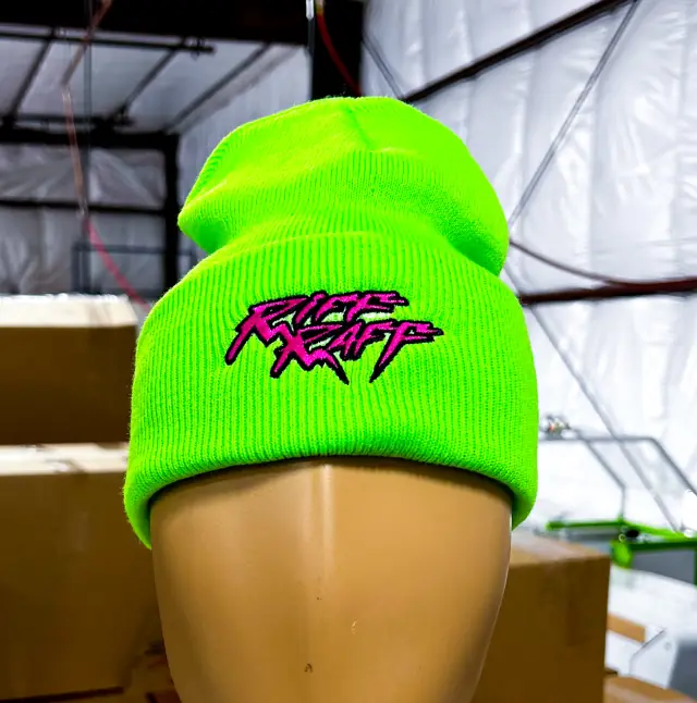 Neon green cuffed knit beanie on a mannequin head with a pink and black embroidered logo on the cuff